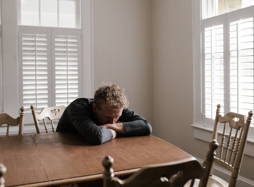 a depressed man leaning on his table