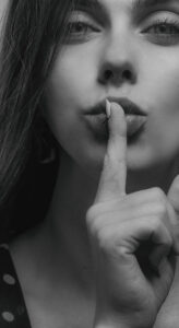 Woman with finger over her lips in black and white