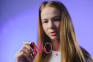 Girl writes "no" on window in lipstick